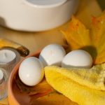 Warm autumn baking setup with eggs, maple leaves, and candles for cozy ambiance.